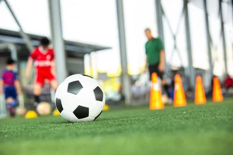 Selective focus to soccer ball on green artificial grass with blurry kids a.. Stock Photos