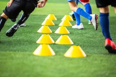 Selective focus to soccer cones with blurry kid legs training soccer on art.. Stock Photos
