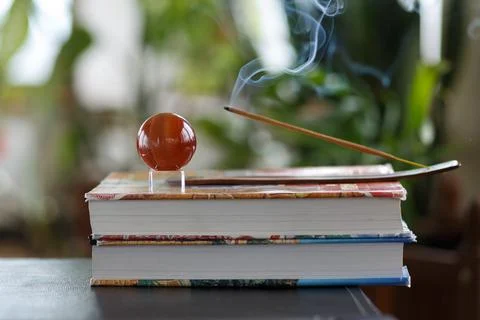 Selective focus, still life with burning incense stick and brown glass ball on a Stock Photos