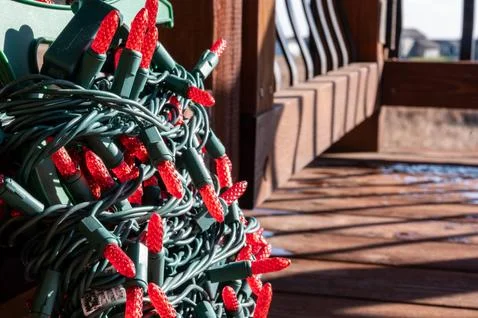 Selective focus on string of Christmas lights being put onto a wooden outdoor Stock Photos