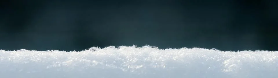 Selective focus on the surface of fresh clean snow on a blurred dark background. Stock Photos