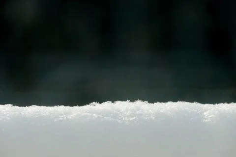 Selective focus on the surface of fresh snow on a dark background. Stock Photos
