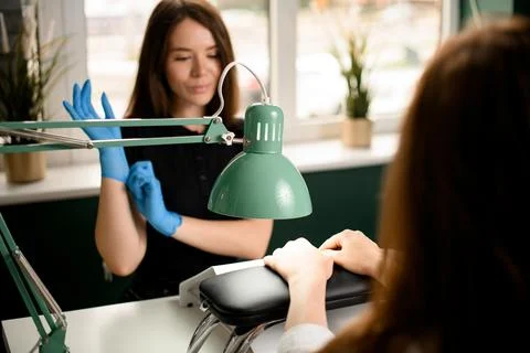 Selective focus on table lamp shining on the hands of female client in nail Foto stock