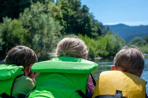 Selective focus on three children peering over a raft going down the wild and Stock Photos