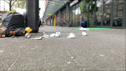 Selective focus. Trash on the city sidewalk near metal trash bin. Environment Video stock 155411877