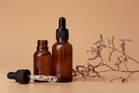 Selective focus, two dark transparent glass bottles with skin serum or oil for Stock Photos