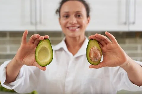 Selective focus on two halves of ripe organic avocado fruits in the hands o.. Stock Photos