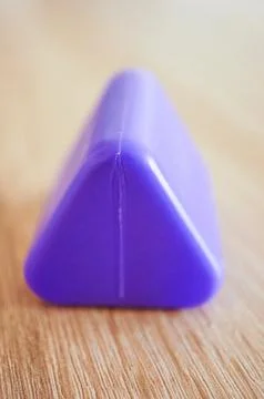 Selective focus vertical shot of a purple triangular prism plastic toy block 스톡 사진