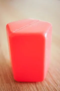 A selective focus vertical shot of a red pentagonal prism plastic toy block w Stock Photos