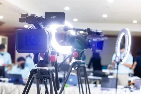 Selective focus to video camera with blurry ring lighting and staff in studio Stockfoto's