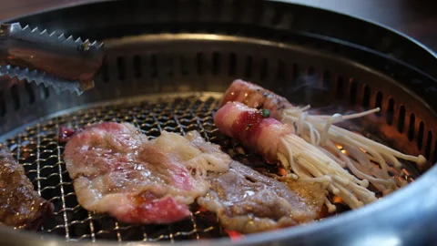 Selective focus view to the mushroom wrapped with bacon meat while being grilled Stock Footage 316069953