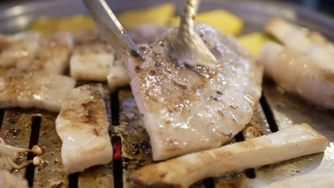Selective focus view using scissor cutting pork meat while being grilled on.. Stock Footage 274485950