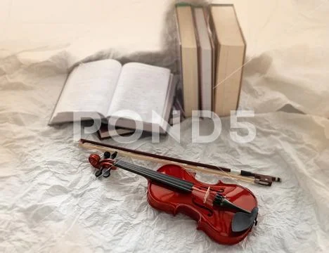 In selective focus of violin and bow put beside books stacked,blurry light de Stock Photos