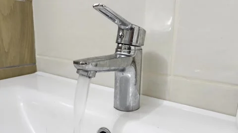 Selective focus on water stream from faucet Stockbeeldmateriaal 313713673