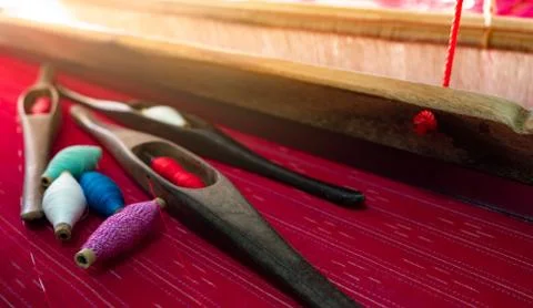 Selective focus on weaving shuttle tool on weaving machine. Red textile fabri Foto stock