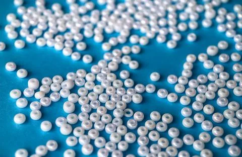 Selective focus, white pearl beads for needlework on a blue background. Making Stock Photos