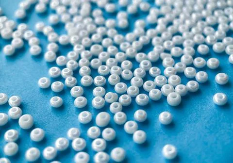 Selective focus, white pearl beads for needlework on a blue background. Making Stock Photos