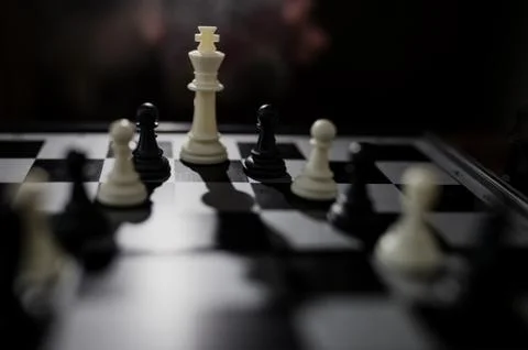 Selective focus of white queen and some black figures on chessboard Stock Photos