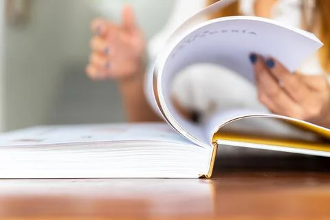 Selective focus of woman's hands turning the pages of a book Stock Photos