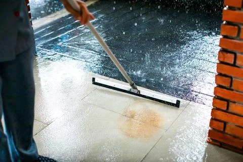 Selective focus to worker using wiper or squeegee to clean floor surface. S.. Stock Photos