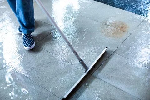 Selective focus to worker using wiper or squeegee to clean floor surface. S.. Stock Photos