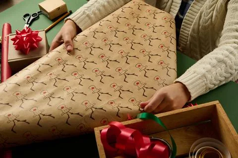 Selective focus on a wrapping gift paper with deer pattern in woman's hands Stock Photos