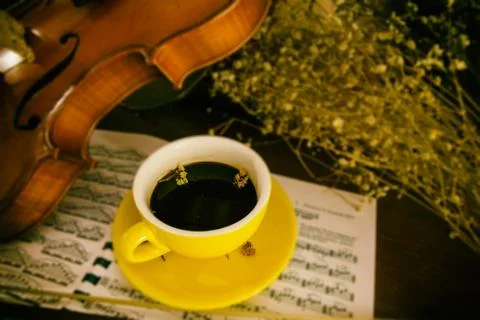 In selective focus of the yellow ceramic coffee cup put beside blurred violin 스톡 사진