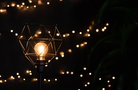 Selective focus yellow light bulb in geometric floor lamp on background. Stock Photos