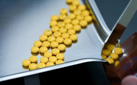 Selective focus on yellow tablets pills on stainless tray with blur hand of.. 写真素材