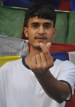 Selective focus of a young guy making Korean love sign with his hand Stock Photos