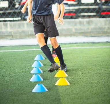 Selective focus to Young soccer player running and stepping through blue an.. Stock Photos