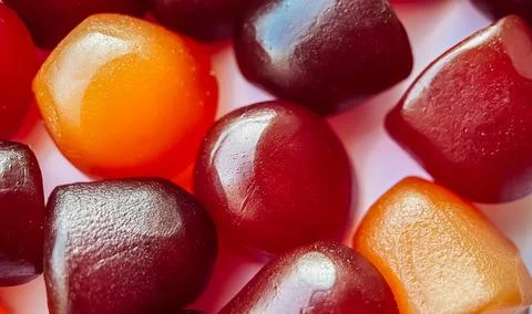 Selective focus.Close-up texture of red, orange and purple multivitamin gummies Stock Photos