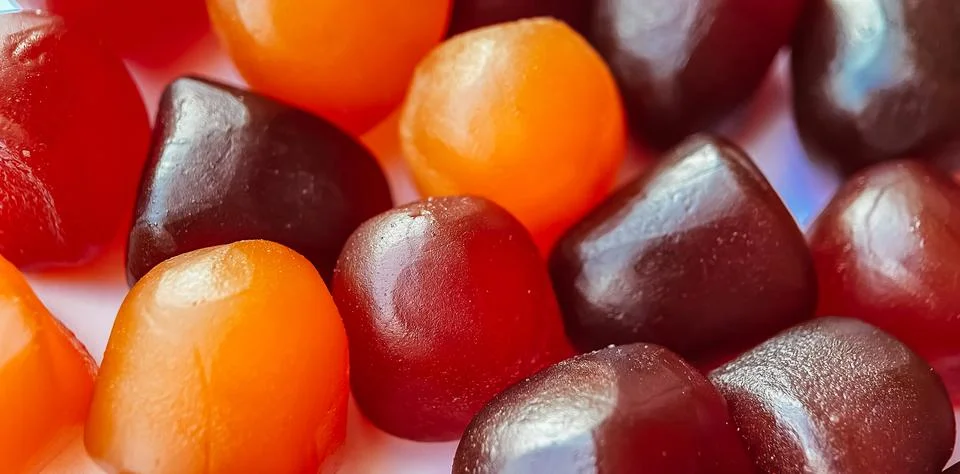 Selective focus.Close-up texture of red, orange and purple multivitamin gummies Stock Photos