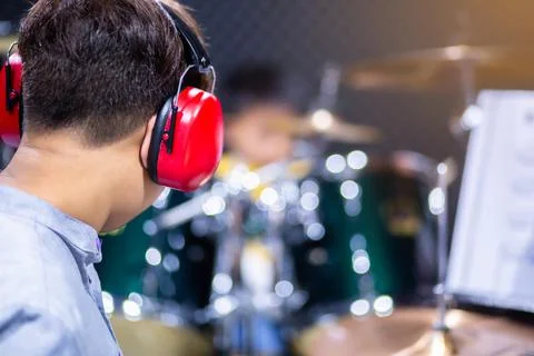 Selective to red ear muffs over head of musicians drummer with blurry the boy Stock Photos