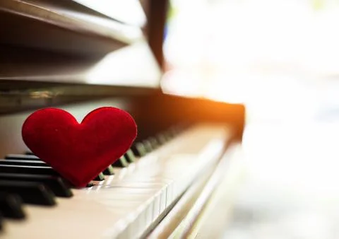 In selective of small red heart put on piano keys,reflection of sunlight is s Foto stock