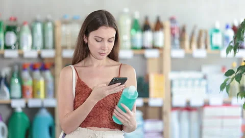 Selective young girl in summer clothes scanning QR-code on shampoo bottle in Stock Footage 310529734