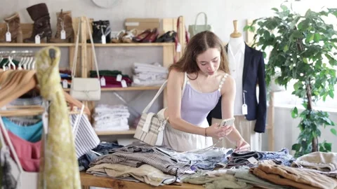 Selective young woman scanning barcode on pantaloons in clothing shop with large Stock Footage 341531864