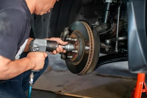 Selevtice focus to professional mechanic using a pneumatic impact wrench to.. Stock Photos