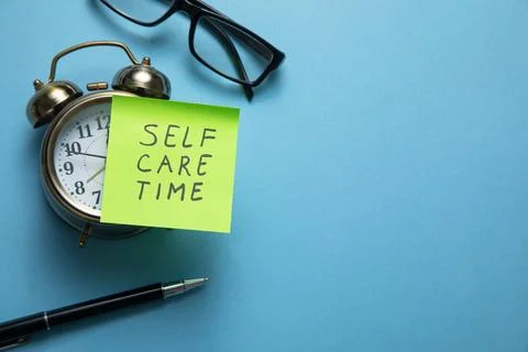 Self care time on sticky note with a clock and business objects. Stock Photos