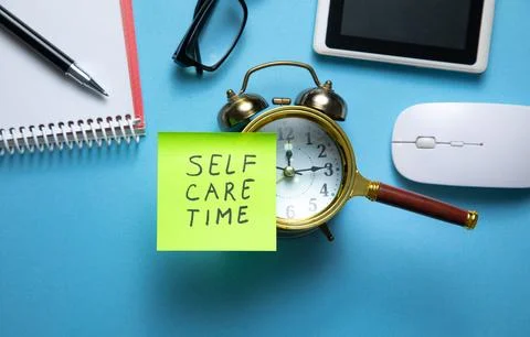 Self care time on sticky note with a clock and business objects. Stock Photos