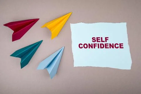 SELF CONFIDENCE. Text on note sheet, paper planes around, symbol of gaining Stock Photos