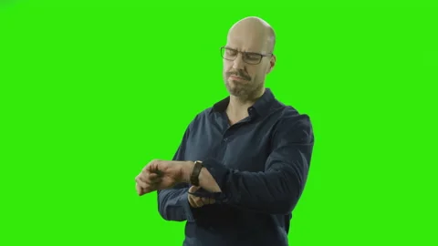 Self-confident man looking at his watch in front of a green screen Stock Footage 166511838
