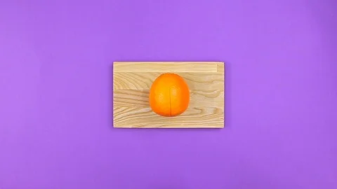 Self cuts orange on board on purple background, top view Vidéo 126529665