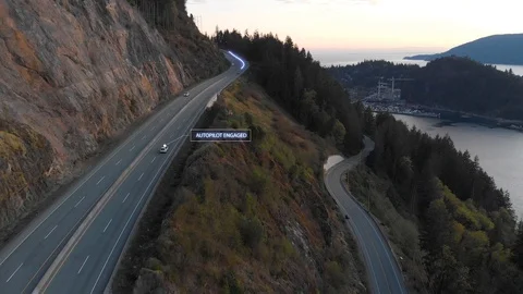 A self driving car travelling down a beautiful coastal highway with a graphical 스톡 동영상 129596500