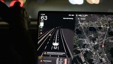 Self-driving Tesla electric car navigating a city road at night Stock Footage 320914815