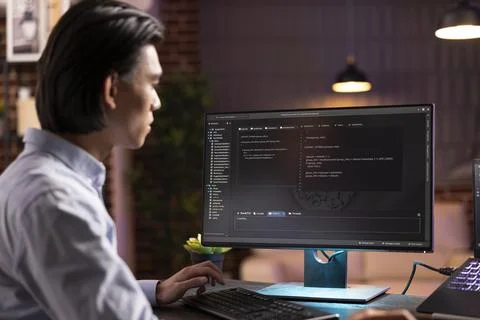 Self employed asian programmer working late at desk Stock-Fotos