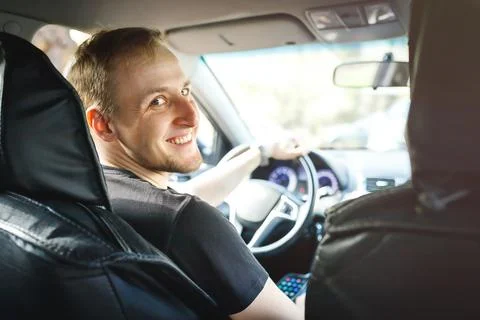 Self-employed caucasian smiling driver in his car taxis or works on delivery Stock Photos