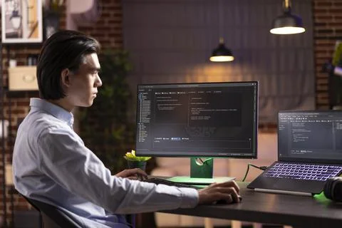 Self employed man working on html codes on multiple screens Stockfoto's
