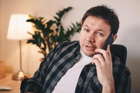 Self-employed young man posing for the camera in his home office, while talki Stock Photos
