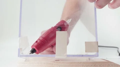 Self-gluing transparent plexiglass with a red glue gun on a white background Stock Footage 182492697